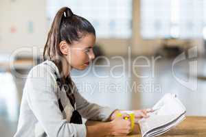 Woman reading newspaper in office