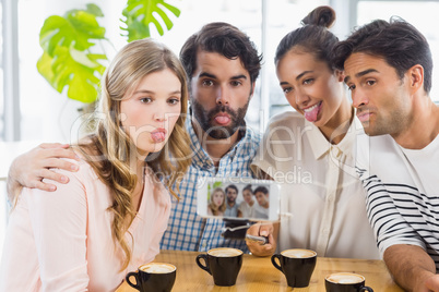 Group of happy friends taking picture with slefie stick