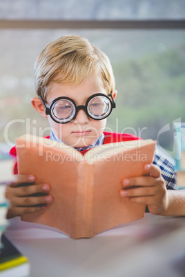 Close-up of schoolkid reading book in classroom