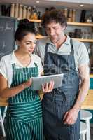Waiter and waitress discussing over digital tablet