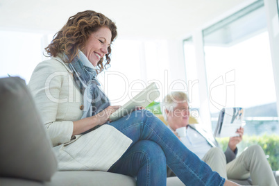 Smiling mature woman by man using digital tablet