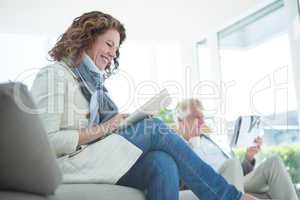 Smiling mature woman by man using digital tablet