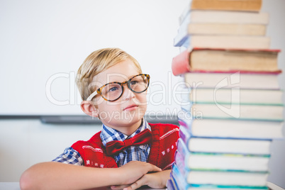 Thoughtful schoolkid pretending to be a teacher in classroom