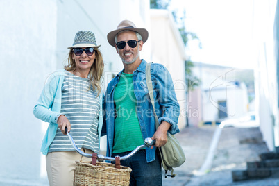 Mature couple with bicycle standing in city