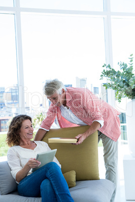 Smiling man giving gift to woman holding tablet