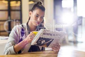 Woman reading newspaper in office