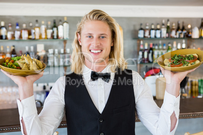 Waiter holding plated meals in restaurant