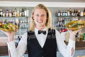 Waiter holding plated meals in restaurant