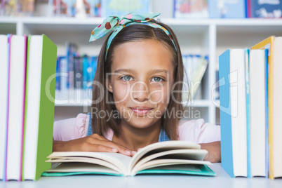 School girl reading a book in library