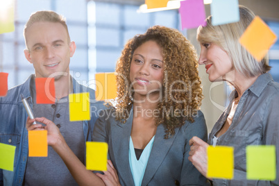 Business people looking at sticky notes stuck to glass