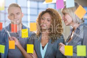 Business people looking at sticky notes stuck to glass