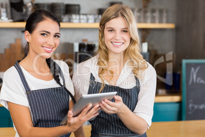 Portrait of two smiling waitresses using digital tablet