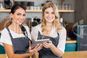 Portrait of two smiling waitresses using digital tablet