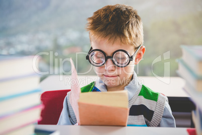 Close-up of schoolkid reading book in classroom