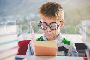 Close-up of schoolkid reading book in classroom