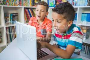 Schoolkids using laptop in library