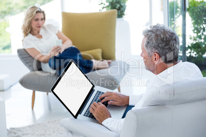 Mature man using laptop by woman