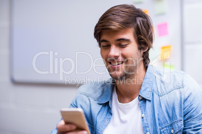 Smiling man using mobile phone in office