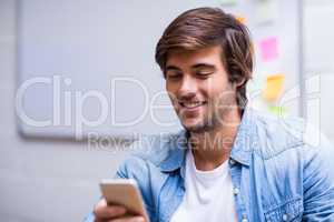 Smiling man using mobile phone in office