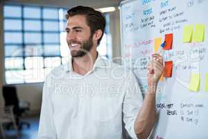 Smiling businessman pointing on sticky note