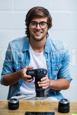 Portrait of happy man holding camera in office