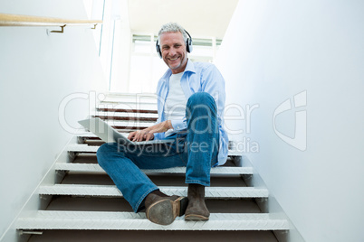 Portrait of smiling man using laptop on steps