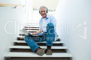 Portrait of smiling man using laptop on steps