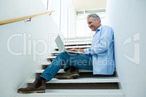 Smiling man using laptop on steps