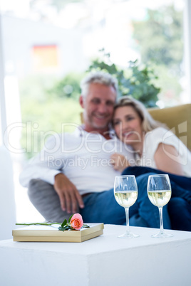 White wine by rose and gift box on table with couple