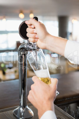 Waiter filling beer from bar pump