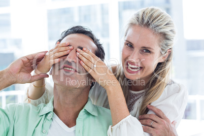 Happy woman covering eyes of man