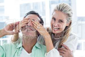 Happy woman covering eyes of man
