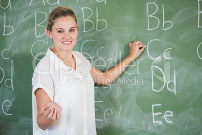 Smiling teacher teaching on chalkboard in classroom