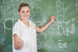 Smiling teacher teaching on chalkboard in classroom