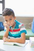 Schoolboy reading a book in library