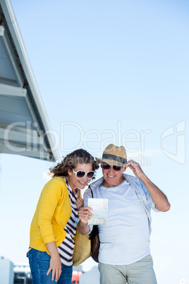 Mature couple reading map against clear sky
