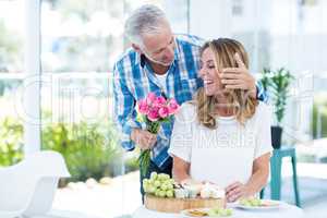 Mature man giving pink roses to happy wife