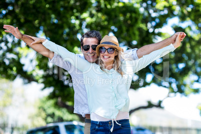 Couple with arms outstretched standing on street