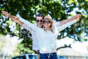 Couple with arms outstretched standing on street