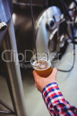 Man holding beer glass by machinery