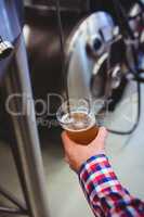 Man holding beer glass by machinery