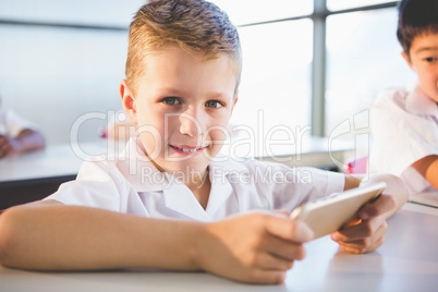 Schoolkid using mobile phone in classroom