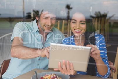 Couple using digital tablet in cafeteria