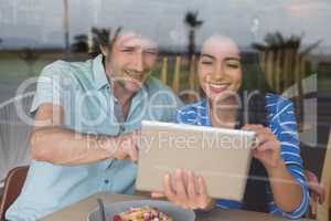 Couple using digital tablet in cafeteria