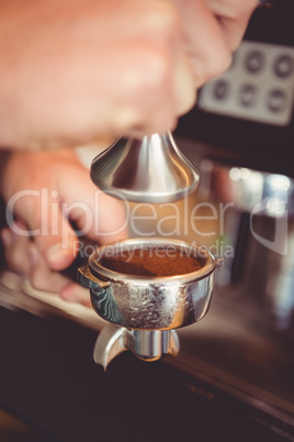 Hands holding tamper with coffee powder