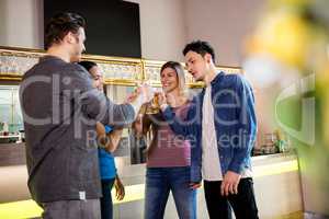 Male and female friends toasting wine at bar