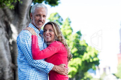 Mature couple hugging against tree