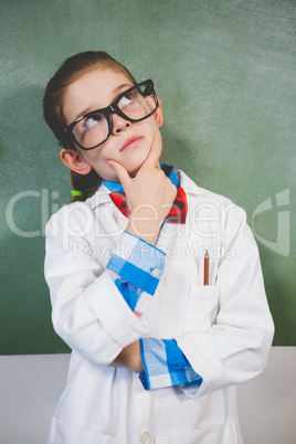 Thoughtful girl standing with hand on chin in classroom