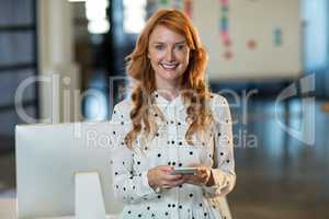 Portrait of smiling woman holding mobile phone in office