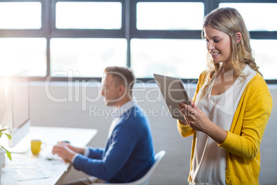 Woman using digital tablet by colleague in office Woman using digital tablet by colleague in office